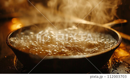 Steaming hot water boils in a pan, with a golden glow reflecting off the bubbles, creating a warm kitchen atmosphere. 112003703