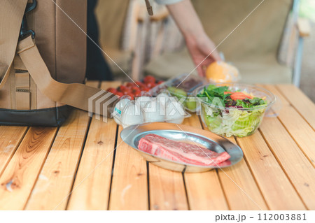 キャンプ場でソフトクーラーボックスから食材を出す女性の手元 キャンプ場でソフトクーラーボックスから食材を出す女性の手元 112003881