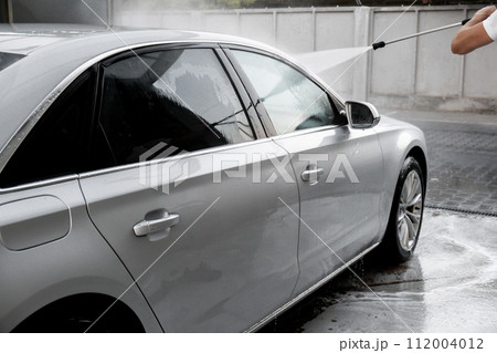 Washing luxury silver car on touchless car wash. Washing sedan car with foam self-service and high pressure water. Winter cleaning in car wash. Cleanliness environment Washing luxury silver car on touchless car wash. Washing sedan car with foam self-service and high pressure water. Winter cleaning in car wash. Cleanliness environment 112004012