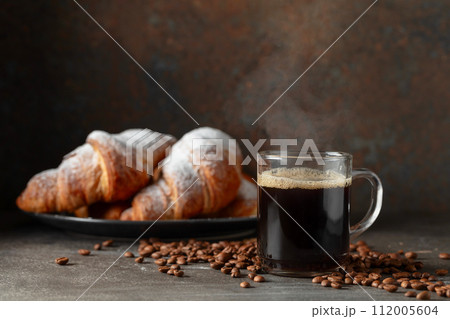 Croissants and black coffee on a kitchen table. Croissants and black coffee on a kitchen table. 112005604