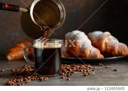 Croissants and black coffee on a kitchen table. Croissants and black coffee on a kitchen table. 112005605