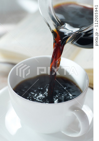 コーヒーカップにコーヒーを注ぐ 読書中のブレイクタイム 112005941