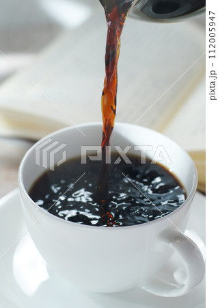 コーヒーカップにコーヒーを注ぐ 読書中のブレイクタイム 112005947
