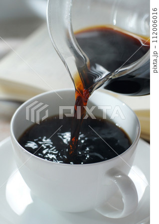 コーヒーカップにコーヒーを注ぐ 読書中のブレイクタイム 112006016