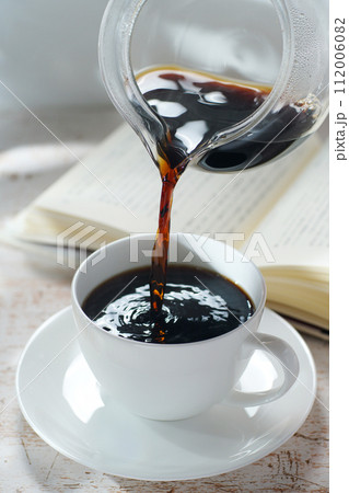 コーヒーカップにコーヒーを注ぐ 読書中のブレイクタイム コーヒーカップにコーヒーを注ぐ 読書中のブレイクタイム 112006082