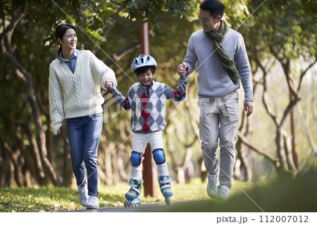 asian parents teaching child roller skating in park 112007012