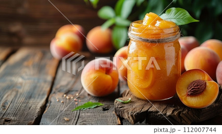 On a wooden table, a jar of canned peaches and fresh peaches are presented side by side large copyspace area, 112007744