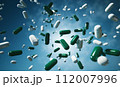 Falling pills green and white capsules against blue background, pharmaceuticals or health supplements. Pharmacist Day and pharmaceutical industry, World Health Day. Banner with copy space 112007996