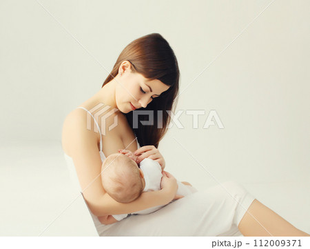 Happy young mother breastfeeding her baby at home on white background Happy young mother breastfeeding her baby at home on white background 112009371