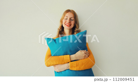 Healthy sleep, happy woman hugs her soft comfortable pillow imagining that she is lying on the bed 112009451