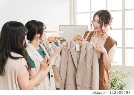 女性買い物客にジャケットをおすすめする女性ショップ店員 112009592