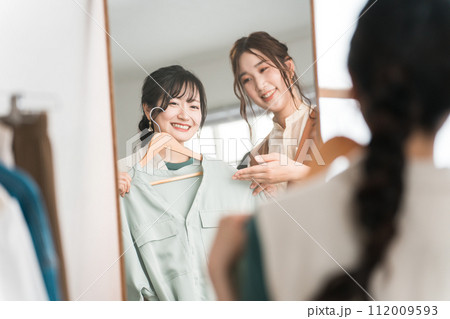 アパレルショップで鏡を見ながら女性店員にコーディネートしてもらう女性買い物客 アパレルショップで鏡を見ながら女性店員にコーディネートしてもらう女性買い物客 112009593