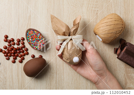 Chocolate eggs with a skein of threads on a wooden background Chocolate eggs with a skein of threads on a wooden background 112010452