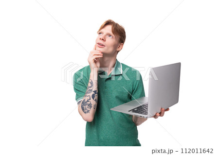 smart cute young redhead guy in a green t-shirt holds a laptop for study and work 112011642
