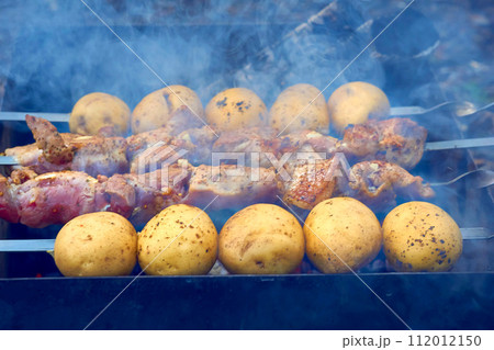 Marinated meat and potatoes on skewers, grilled over hot coal 112012150