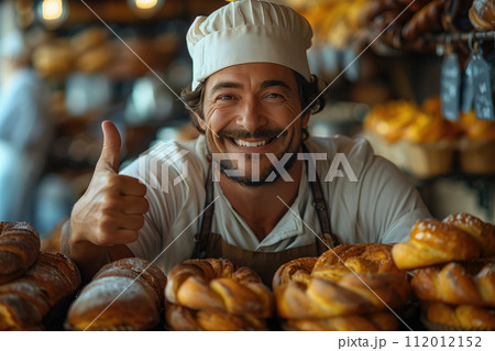 Portrait of smiling male baker showing thumbs up while standing in bakery 112012152