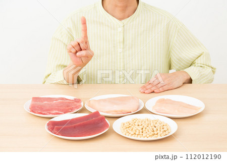 タンパク質の多い食材と人差し指を立てるミドル女性 タンパク質の多い食材と人差し指を立てるミドル女性 112012190