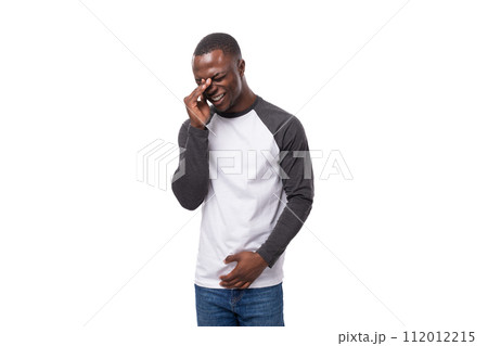 young african man with short haircut dressed in a sweatshirt and jeans is embarrassed and worried young african man with short haircut dressed in a sweatshirt and jeans is embarrassed and worried 112012215