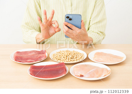 タンパク質の多い食材とスマホを操作するミドル女性 タンパク質の多い食材とスマホを操作するミドル女性 112012339