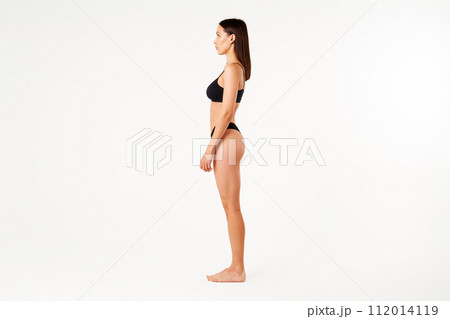 Profile view of full length portrait of beautiful sensual slim woman in black underwear 112014119