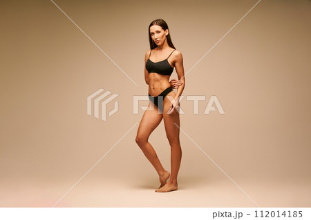 Pretty sporty woman in black underwear posing on beige studio background Pretty sporty woman in black underwear posing on beige studio background 112014185