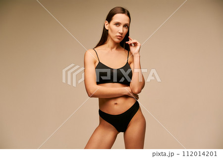Beautiful sporty woman in black underwear posing on beige studio background 112014201