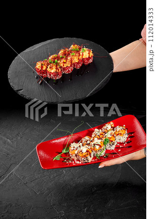 Female hands presenting two varieties of sushi rolls Female hands presenting two varieties of sushi rolls 112014333