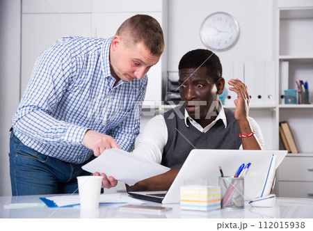 Interracial men working in office room with documents 112015938