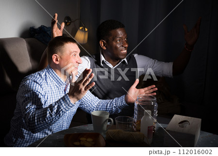 Two excited male interracial friends watching football game Two excited male interracial friends watching football game 112016002