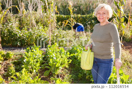 Woman holding watering can in her hands 112016554