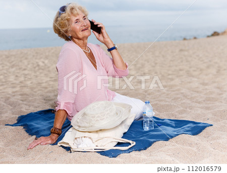 Aged woman talking on phone outdoors Aged woman talking on phone outdoors 112016579
