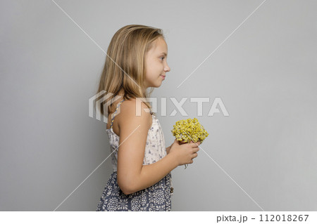 Joyful young child girl wearing summer dress holding yellow flower standing Joyful young child girl wearing summer dress holding yellow flower standing 112018267
