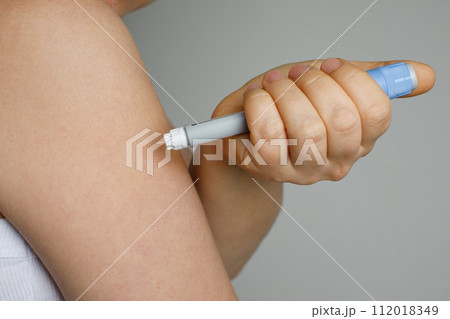 Blue self injection pen near female shoulder. Medicine and treatment concept 112018349