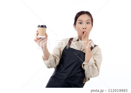 Cheerful young asian woman barista in casual work attire happily holding a takeaway coffee cup. Cheerful young asian woman barista in casual work attire happily holding a takeaway coffee cup. 112019985