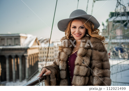 Portrait of happy brunette woman wearing re ress, fur mink winter coat and grey hat  112021499