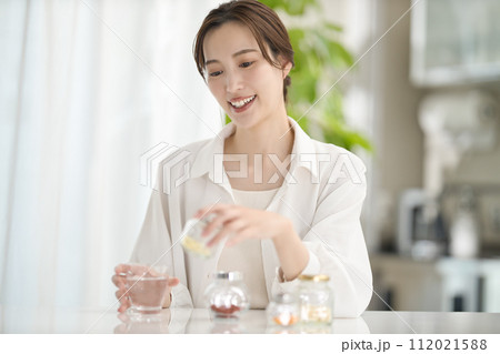 リビングでサプリメントを飲む女性 112021588
