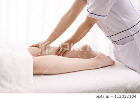 エステティシャンにフットマッサージを受ける女性 112022104