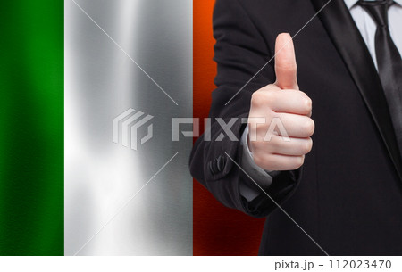 Irish concept. Businessman showing thumb up on the background of flag of Ireland Irish concept. Businessman showing thumb up on the background of flag of Ireland 112023470