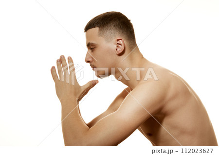 Side view of thoughtful shirtless man with serious and focused expression folded his hands together against white studio background. Side view of thoughtful shirtless man with serious and focused expression folded his hands together against white studio background. 112023627