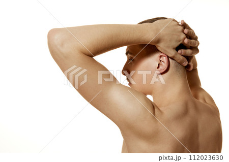 Rear view portrait of young man holds his hands behind head against white studio background. Model showing his back muscles. Rear view portrait of young man holds his hands behind head against white studio background. Model showing his back muscles. 112023630