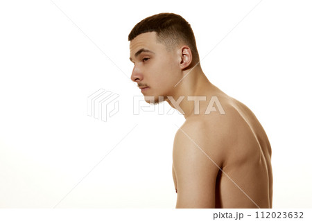 Side view photo of young man slouches against white studio background. Incorrect posture, beauty and confidence. Side view photo of young man slouches against white studio background. Incorrect posture, beauty and confidence. 112023632