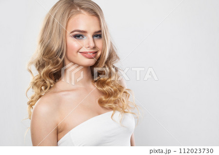Smiling blonde model woman with perfect hairstyle, fresh clear skin and makeup on white background.  112023730