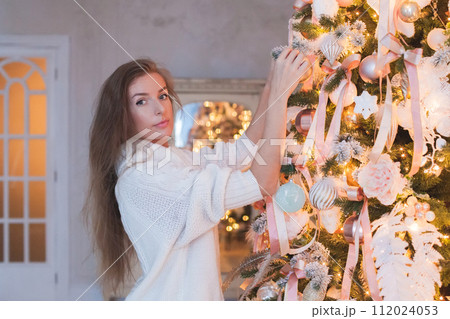 Cute woman decorating the Christmas tree at home 112024053