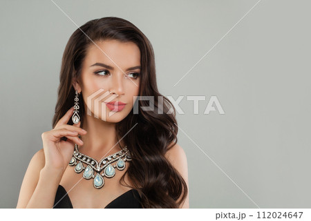 Pretty young brunette model woman with long wavy hairdo, diamond jewelry earring and necklace Pretty young brunette model woman with long wavy hairdo, diamond jewelry earring and necklace 112024647