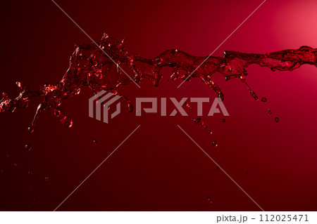 Red wine splash on a dark red background. Red wine splash on a dark red background. 112025471