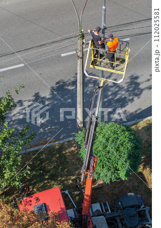 Workers installing a new street lamp. Workers installing a new street lamp. 112025581