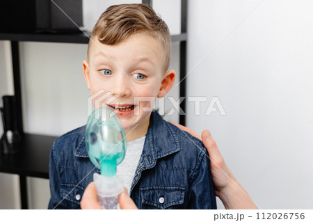Cute boy shows displeasure emotion before inhaling 112026756