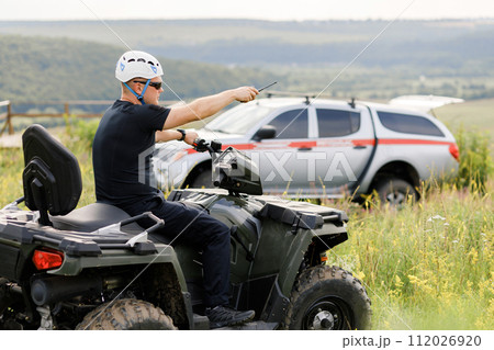 The rescuer, a beautiful athletic physique, rides an ATV in the middle of the field 112026920
