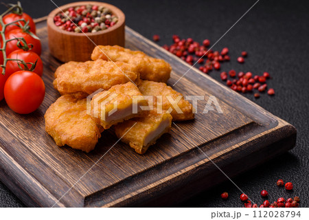 Delicious fresh crispy chicken nuggets on a dark concrete background 112028794