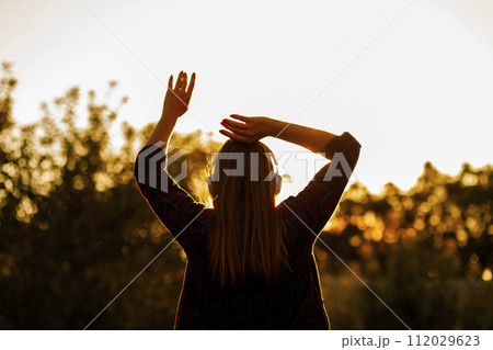 Woman with Headphones Enjoying Sunset Silhouette Woman with Headphones Enjoying Sunset Silhouette 112029623